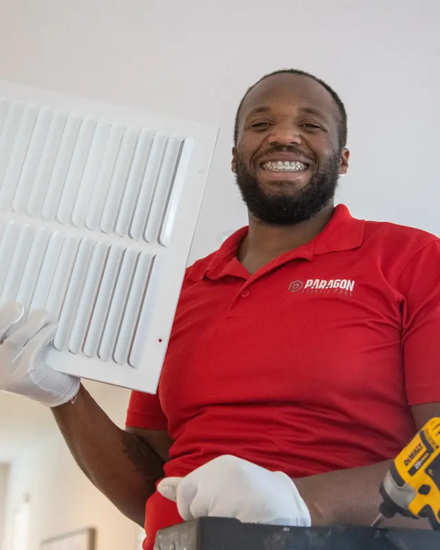 Smiling Paragon technician removing a return-air grille to change the filter