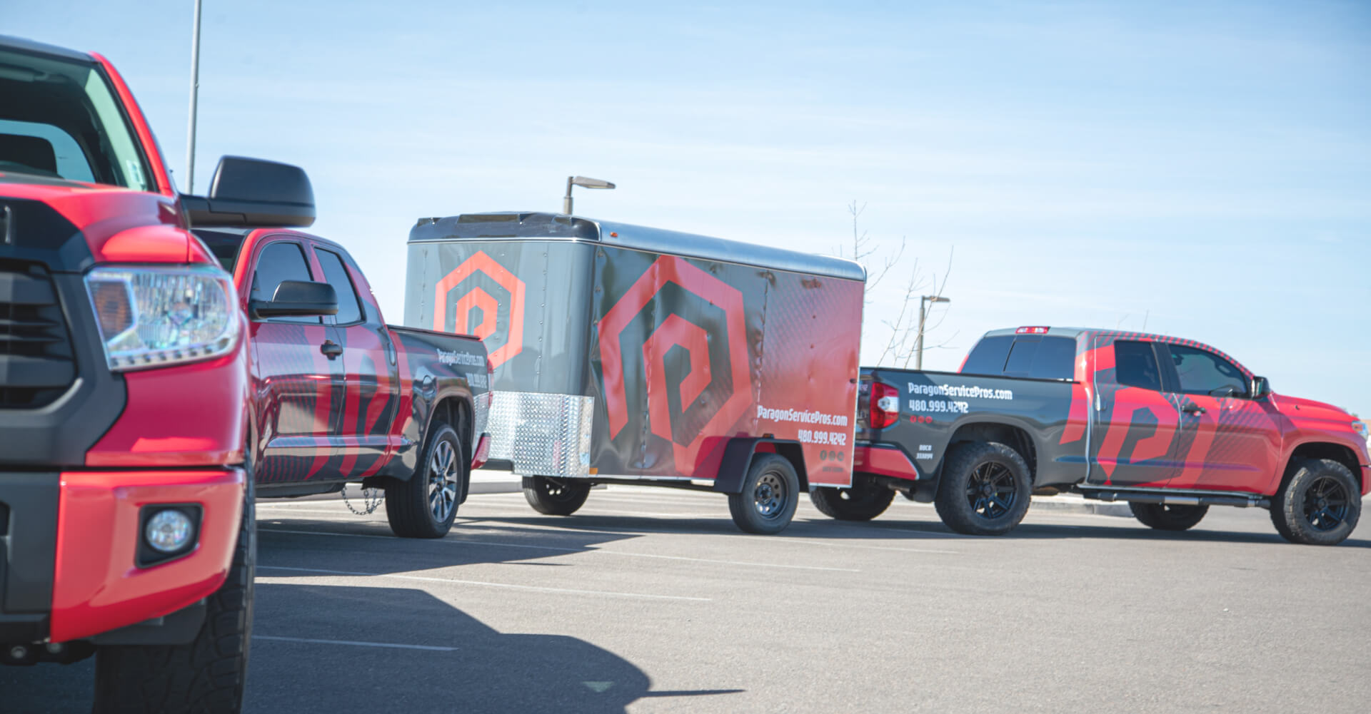 Toyota trucks featuring red and black graphics parked in a lot, showcasing Paragon Services Pros branding.
