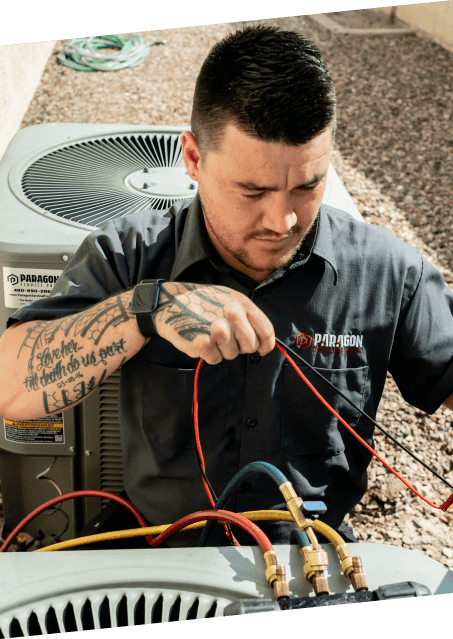 A technician from Paragon Service Pros repairs an air conditioner, focused on ensuring optimal performance.