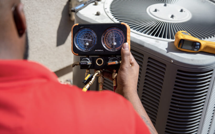 A technician from Paragon Service Pros checks an air conditioner using a meter for accurate diagnostics.