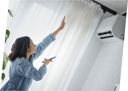 A woman is reaching for a window air conditioner, showcasing the services of Paragon Service Pros in home comfort solutions.