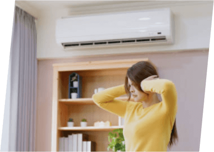 A woman stands in front of a room air conditioner, showcasing the services of Paragon Service Pros.
