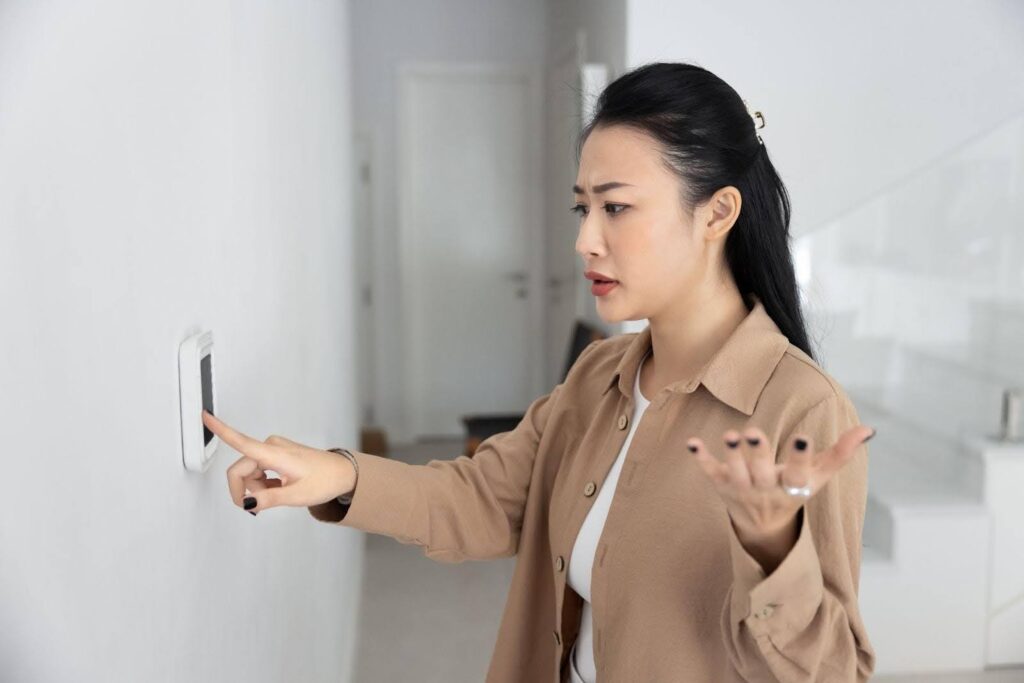 A woman points at a light switch indicating a desire to turn the light on or off